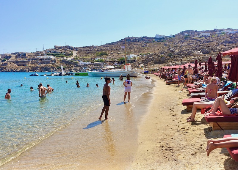 Sunbathers, swimmers, and boats on Super Paradise Beach in Mykonos