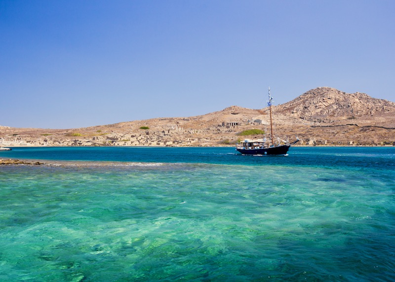 A boat sailing past Delos Island off the coast of Mykonos