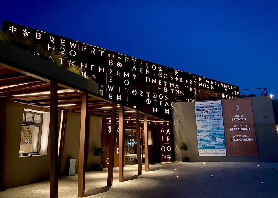 Exterior with illuminated letters of Ftelos Brewery in Karterados, Santorini