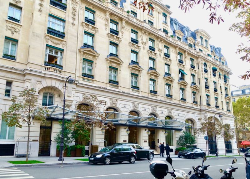 Ornate exterior of a fancy hotel on a street in Paris.