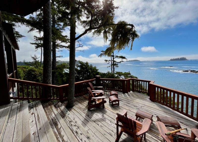 View of the pacific ocean through the pines from a spacious wooden deck with adirondack chairs