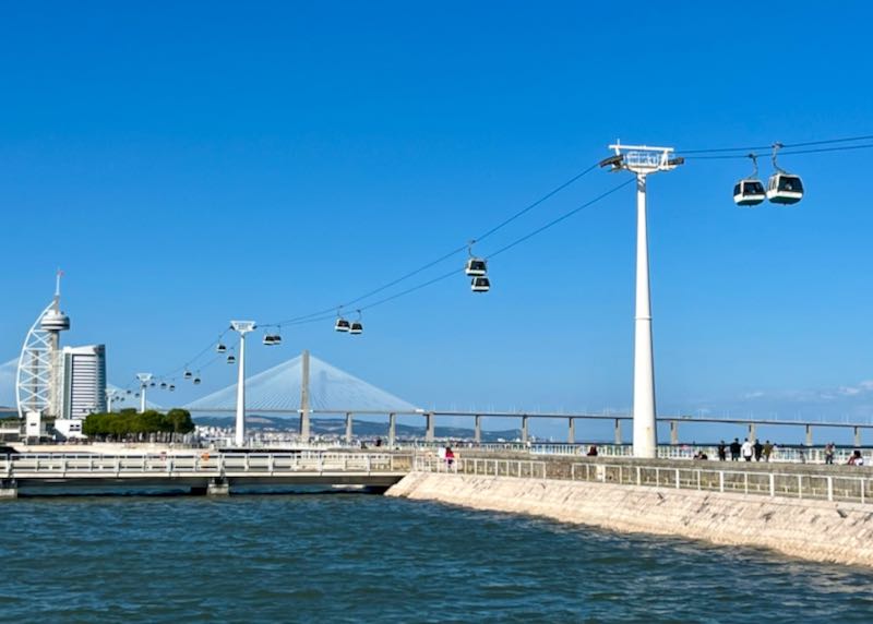 Aerial trams run over a seawall on a sunny day
