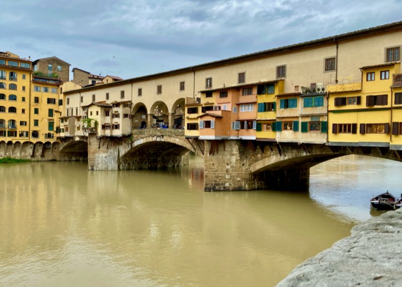 View of the colorful Ponte Vecchio bridge from the banks of the Arno River