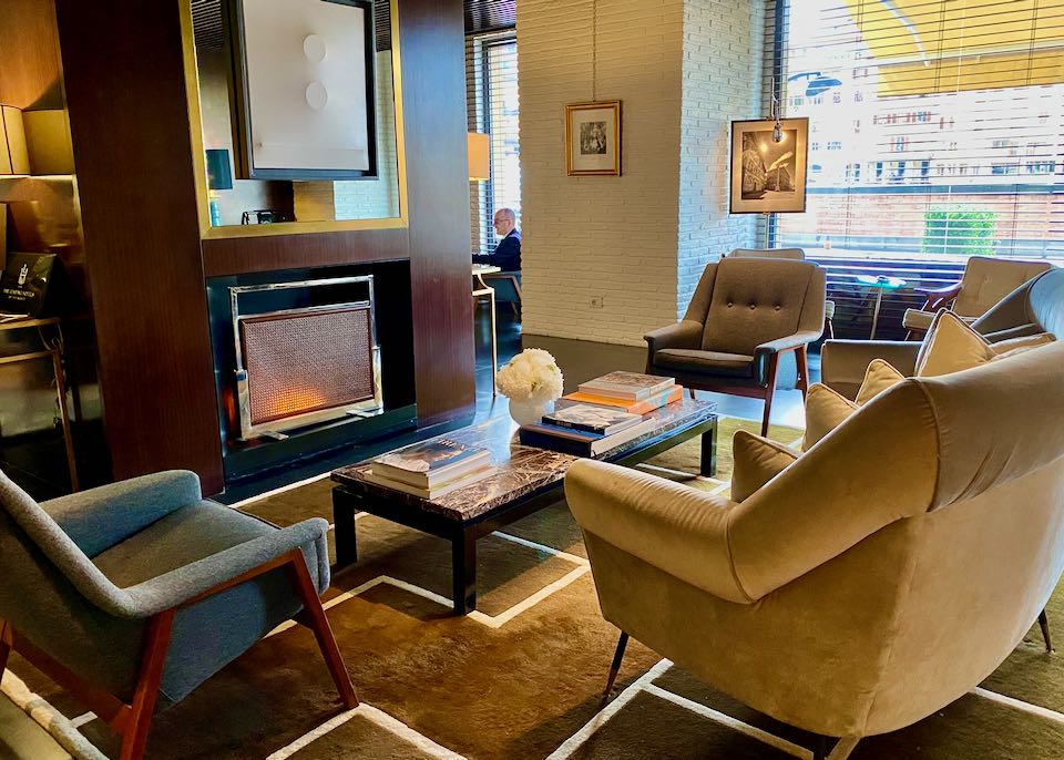 Plush chairs and a sofa centered around an stylish electric fireplace in a hotel lobby