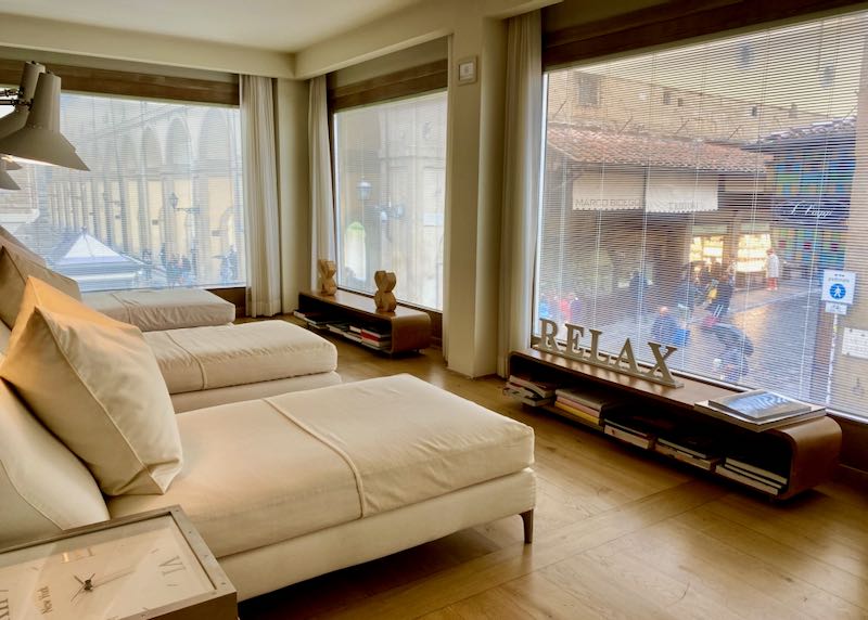 Room with daybeds looking out floor-to-ceiling windows over the Ponte Vecchio in Florence