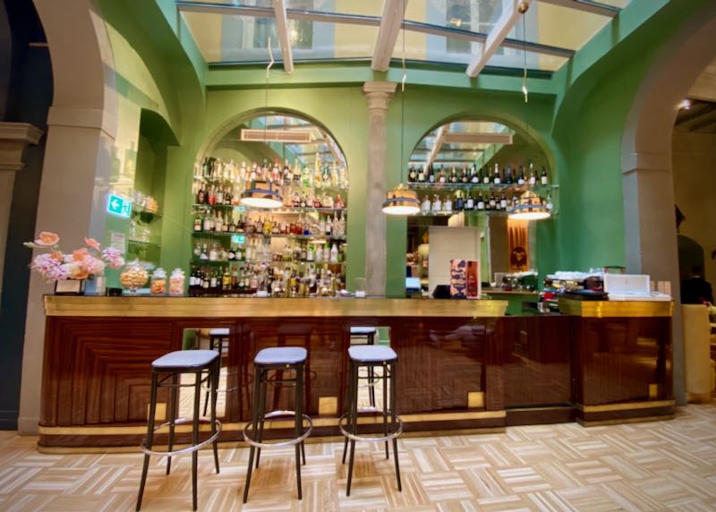 Bright green hotel bar, lit by a large skylight