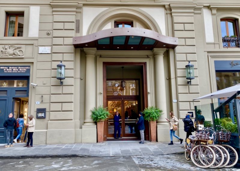 Exterior of a hotel entrance with doorman and bikes parked in front