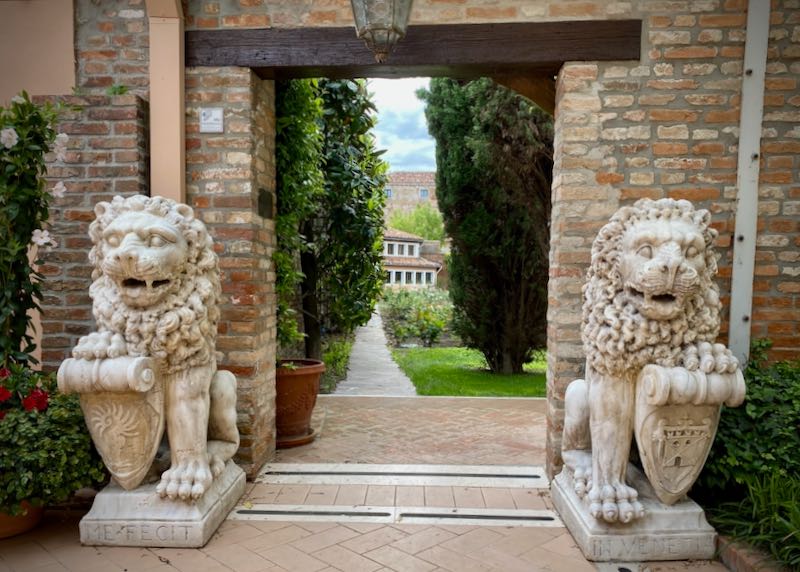 Stone lions flanking a doorway, with a view through to a leafy lawn and garden path