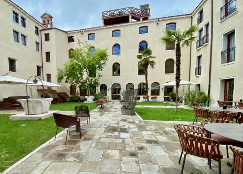 Hotel courtyard with cafe tables set amid grass and palm trees