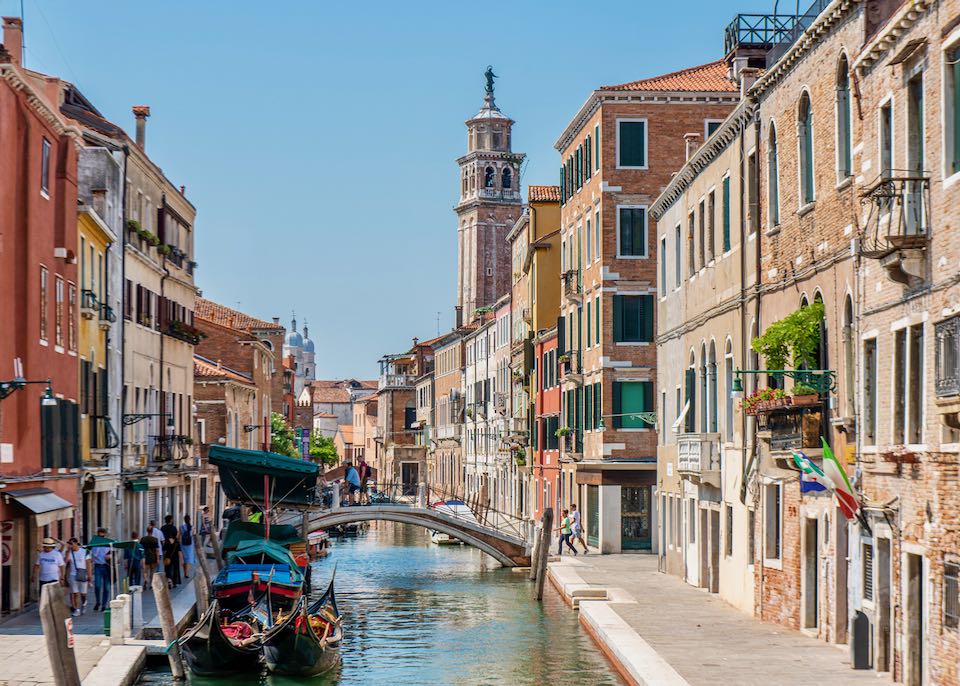 People walking next to a small bridge over the water canal in the Dorsoduro district at Venice, Italy.