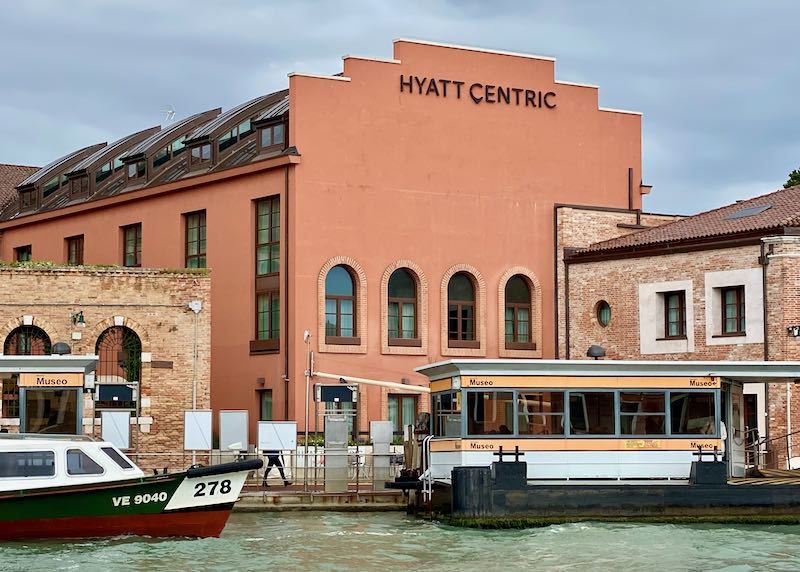 A waterbus stop in front of the modern facade of the Hyatt Centric hotel in Murano.