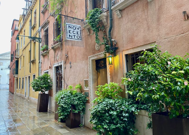 A hotel sign hangs on a pink-painted rustic Venetian building