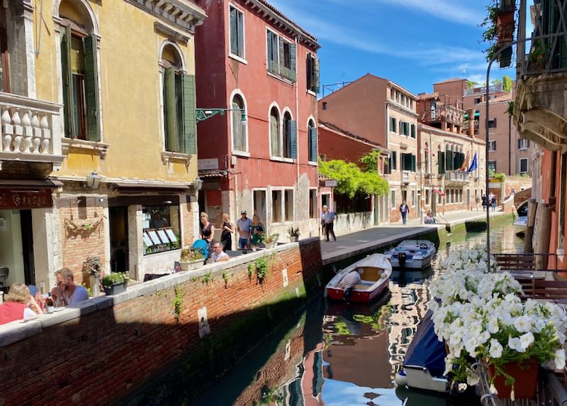 View down a small canal of colorful Venetian buildings on a sunny day