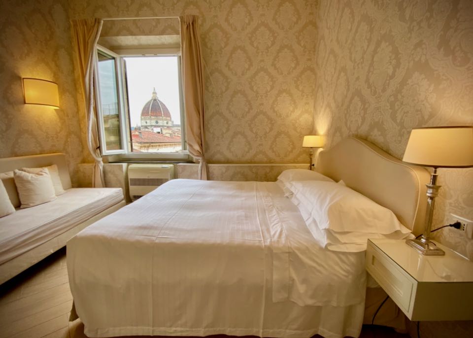 Simple but elegant hotel room with an open window showing an incredible view of the Duomo in Florence