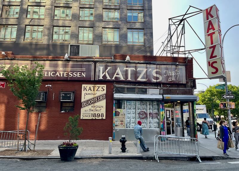 Exterior of Katz's Delicatessen on New York's Lower East Side, with a young man lounging in front