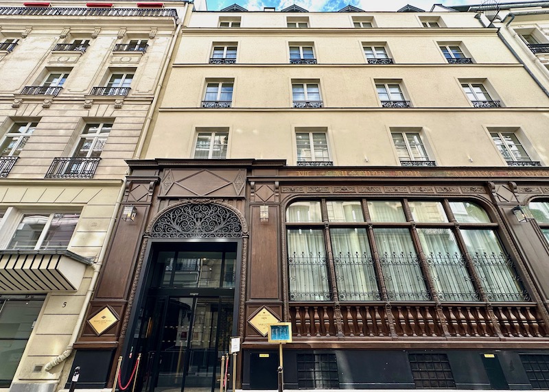 Ornate dark wood and iron facade with four stories above at the entrance to the Maison Albar Vendome in Paris.