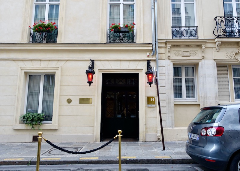 Two red lanterns on either side of a black door mark the entrance to Maison Souquet in Paris