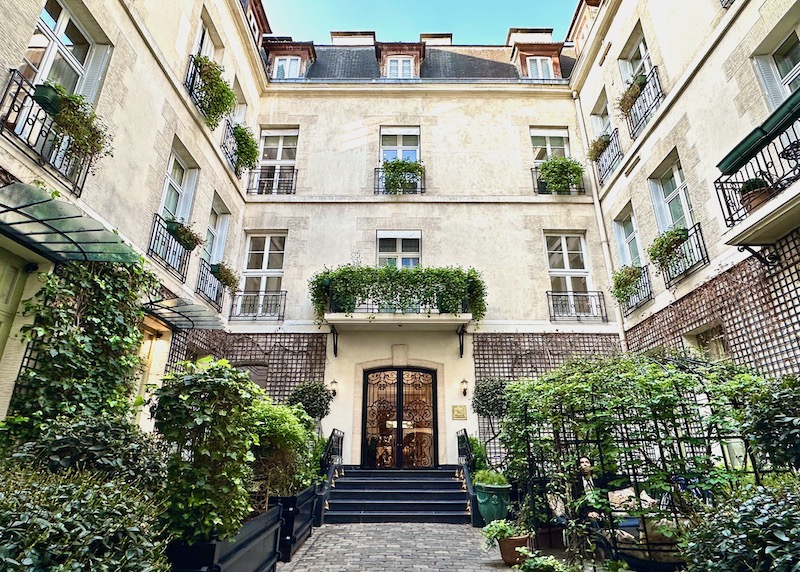 The vine and shrub-filled entrance courtyard of the Relais Christine in Paris