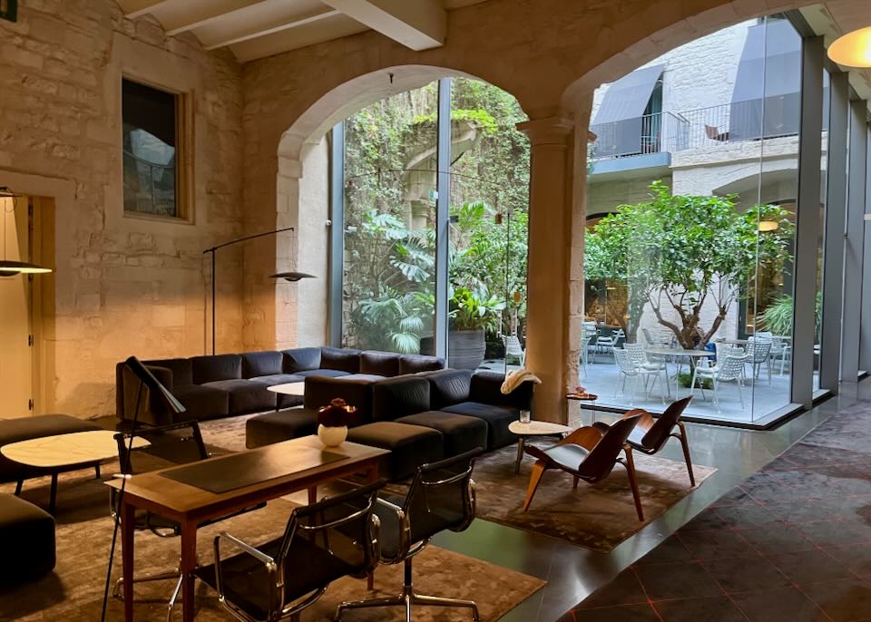 Hotel lobby with leather sofas and floor-to-ceiling views of an exterior courtyard