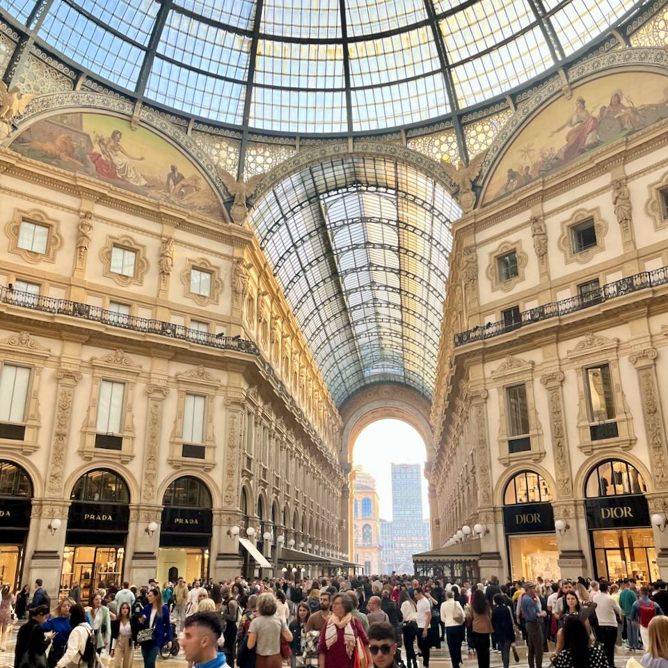 Bright, cavernous, and ornate interior of the Gallerie shopping center in Milan, lit with golden dusky light