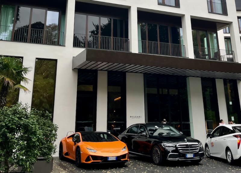 Expensive sports cars parked outside of a modern, stylish hotel