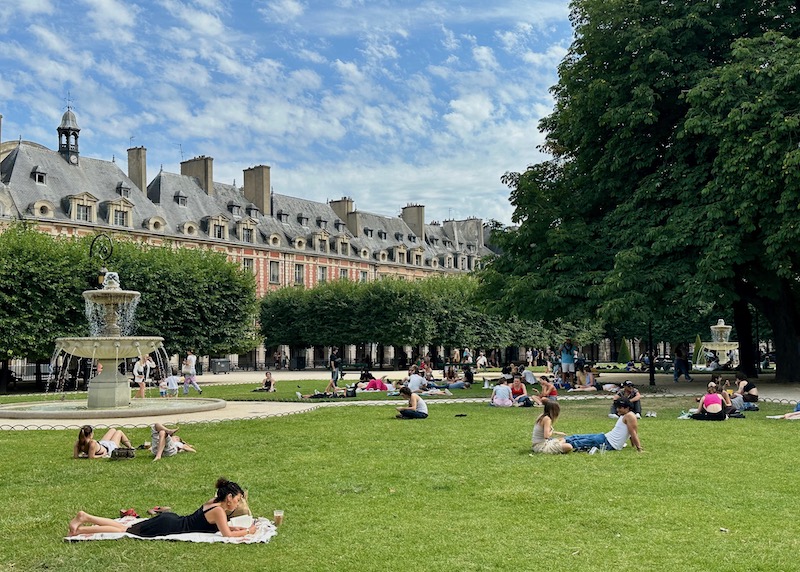 People enjoying the park at Place des Vosges in Le Marais in the 4th Arrondissement of Paris