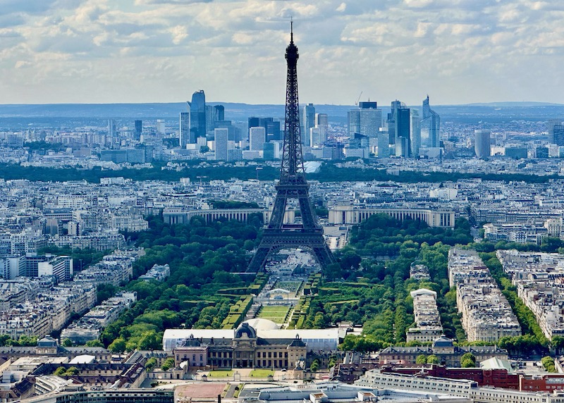 View of the Eiffel Tower with Champ de Mars park in front and skyscrapers behind in Paris