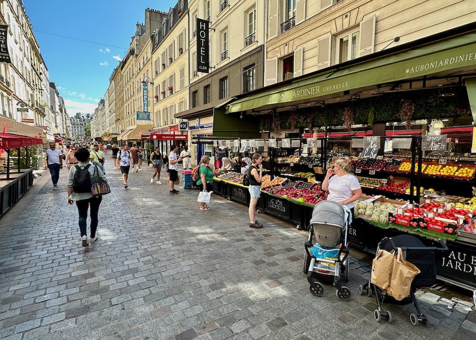 Rue Cler pedestrian shopping street with stone pavers, a fruit stand, and symmetrical buildings in Paris