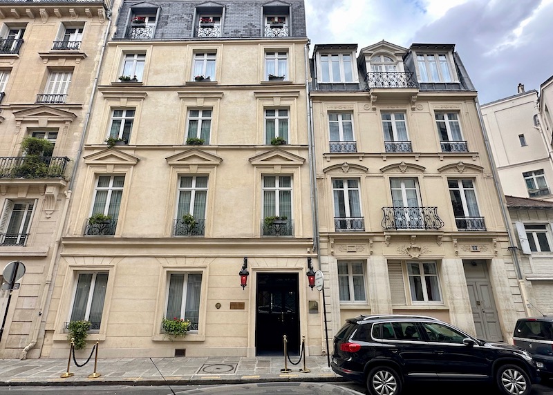 Understated exterior of Maison Souquet hotel with planters at every window and red lanterns marking the entrance in the 9th Arrondissement of Paris