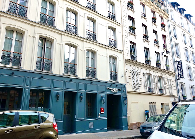 Exterior of the Hotel Saint-Louis Pigalle with blue on the ground floor, cream on top, and wrought iron railings in the 9th Arrondissement of Paris
