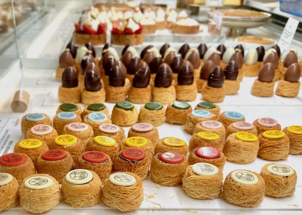 Close up view of rows of shredded pastry nests with colorful chocolate caps and chocolate eggs at Maison Aleph in Paris
