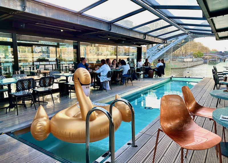 Covered pool with a golden swan float inside the bar and restaurant of OFF Paris Seine with a view on the river