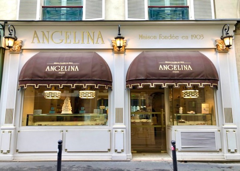 Exterior of Angelina patisserie with two matching brown awnings with gold trim in Paris
