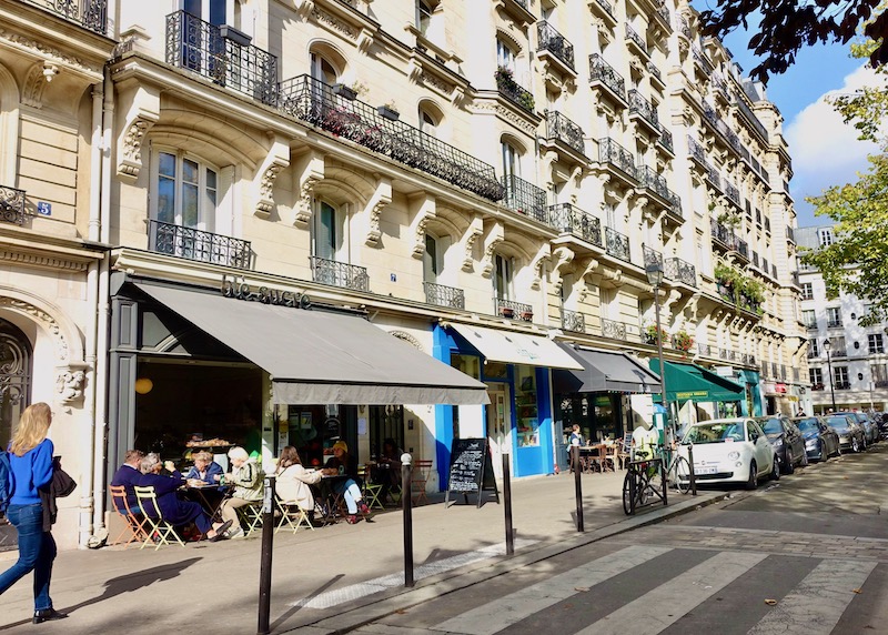 Exterior of Blé Sucré bakery with a gray awning and sidewalk tables set up in Paris