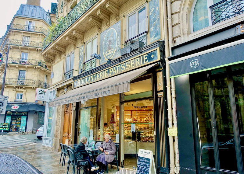 Exterior of bakery Eric Kayser with friends sitting at a table on the sidewalk in Paris