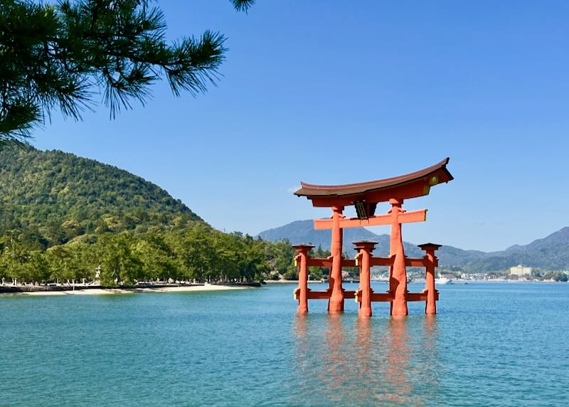A wood red shrine structure sits in a lake.