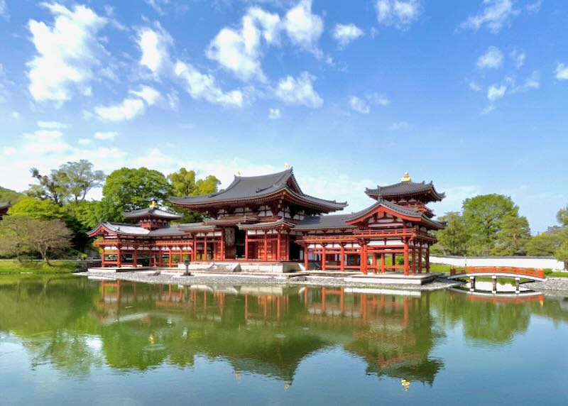 A red Japanese temple sits by the green lake.
