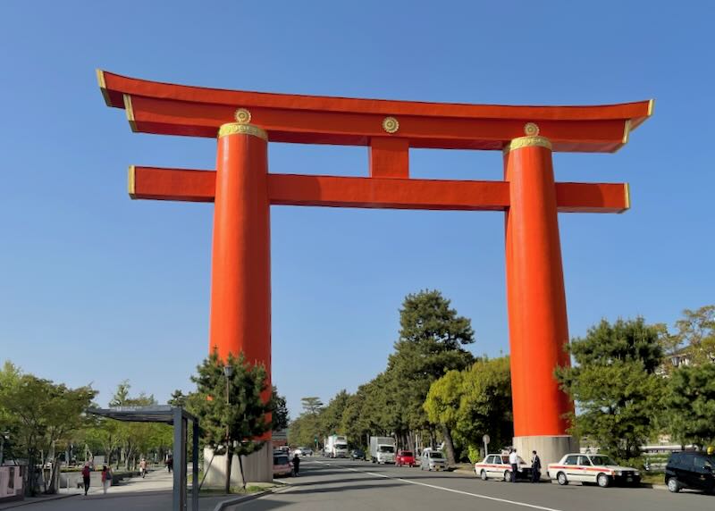 A tall red pillared torii gate sits over the road.