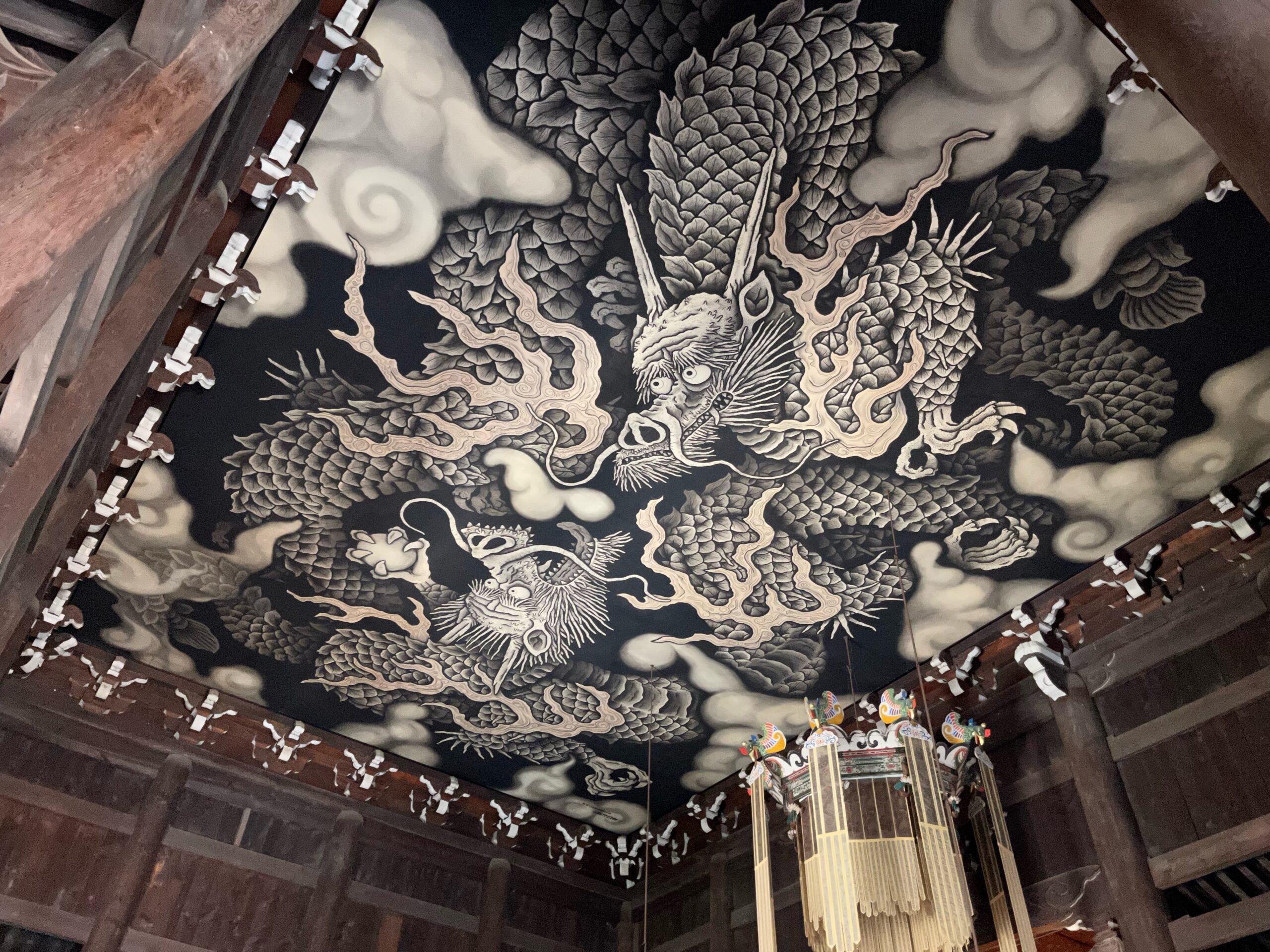 A ceiling painting of two dragons in black and white, with straight horns, fire, and white swirly clouds in Kennin-ji Temple.