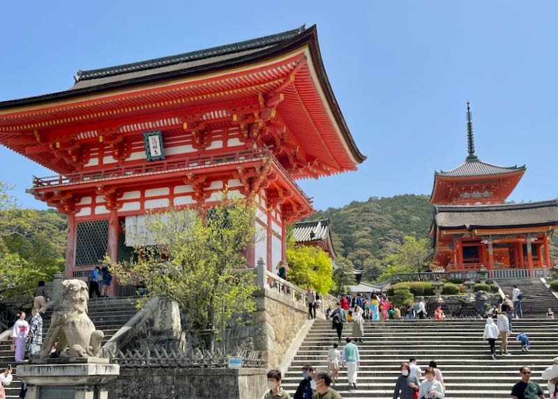 Two red temples sit on cliffs accessed by stairs.