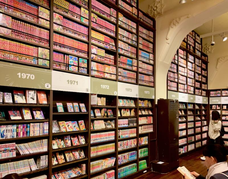 A museum of Japanese graphic novels lines the walls on shelves to the ceiling.