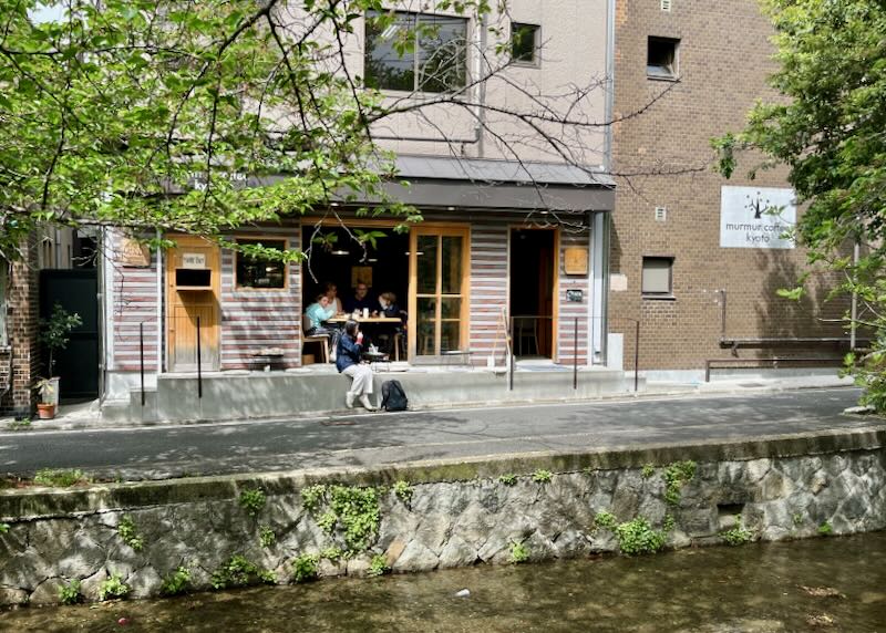 People sit in a coffee shop by a stone river canal in Japan.