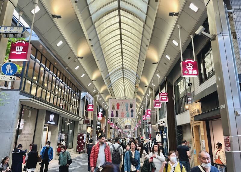People walk through a bright covered shopping mall.