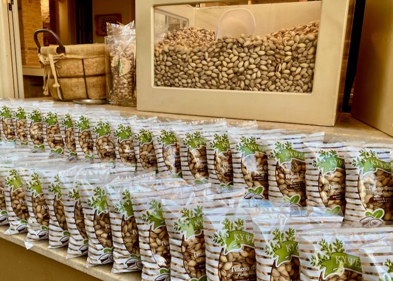 Bags of pistachio nuts are arranged in front of a large bin of the same