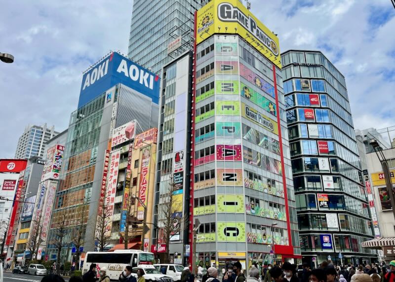 A corner with tall, colorful buildings advertising Japanese electronics stores.