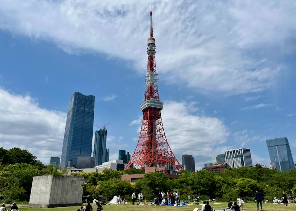 People picnic on the grass in front of the iconic red Tokyo Tower
