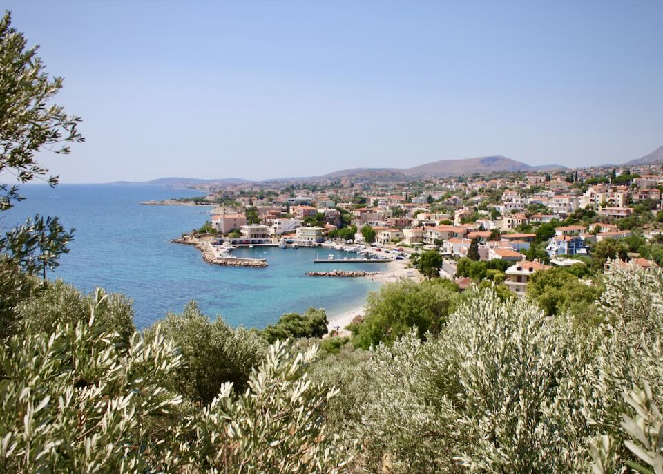 View over a Greek fishing harbor, as seen through sagey-green foliage
