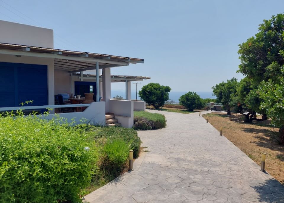 Crushed gravel path leading past Greek-style villas with a sea view