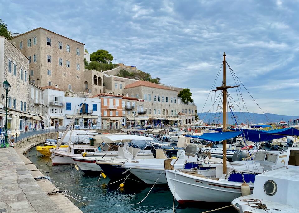 Greek fishing boats moored in a harbor lined with rustic stone buildings