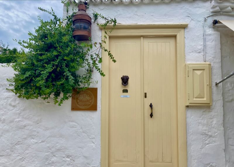 Yellow door in a rustic white stucco building with a tiled roof